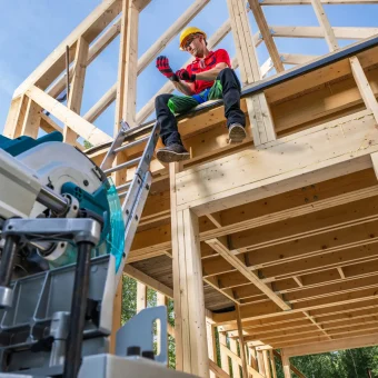 Professional Caucasian Wooden House Skeleton Frame Contractor Worker in His 40s Seating on the House Top Level